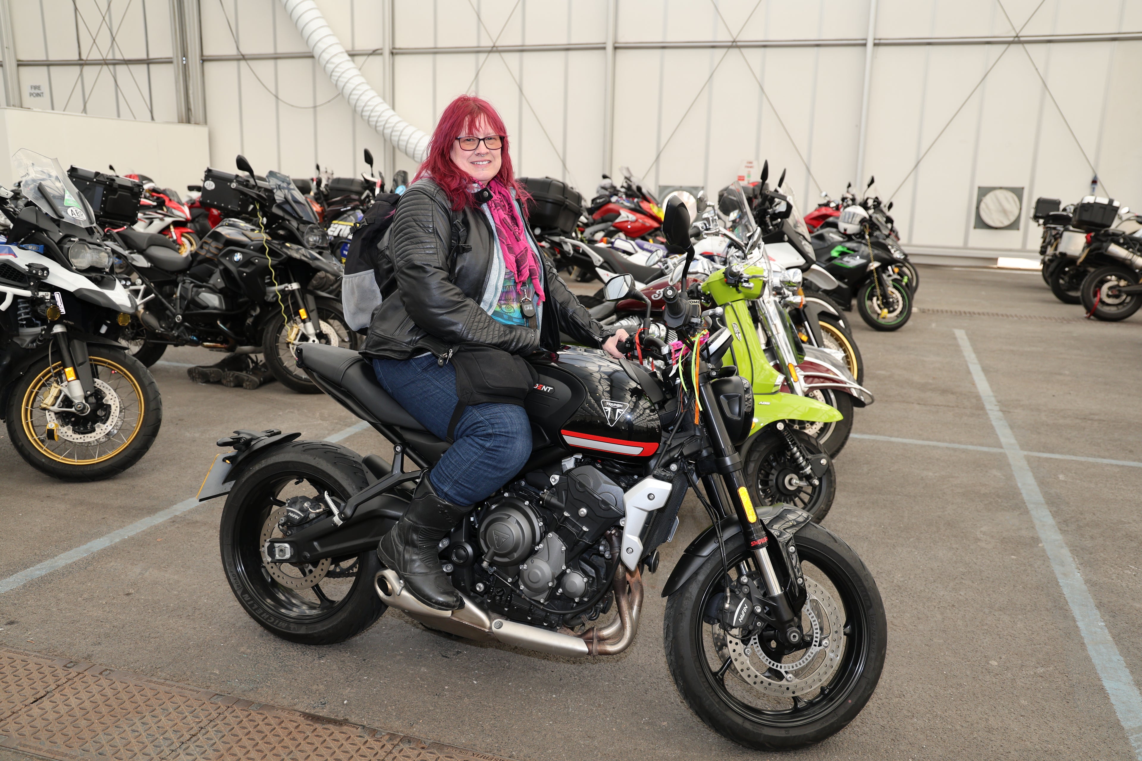 Woman rider with pink hair sitting on a Triumph motorcycle at the MCL motorcycle show