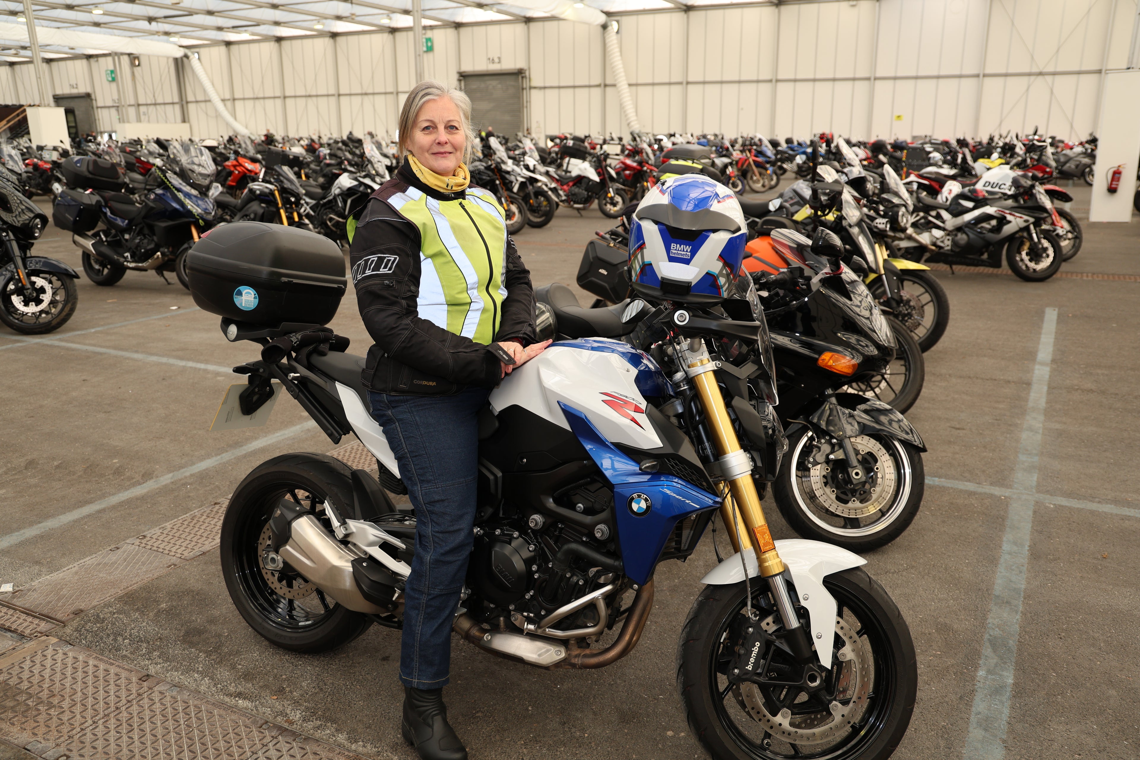 Woman rider sitting on a blue and white BMW motorcycle at the MCL motorcycle show